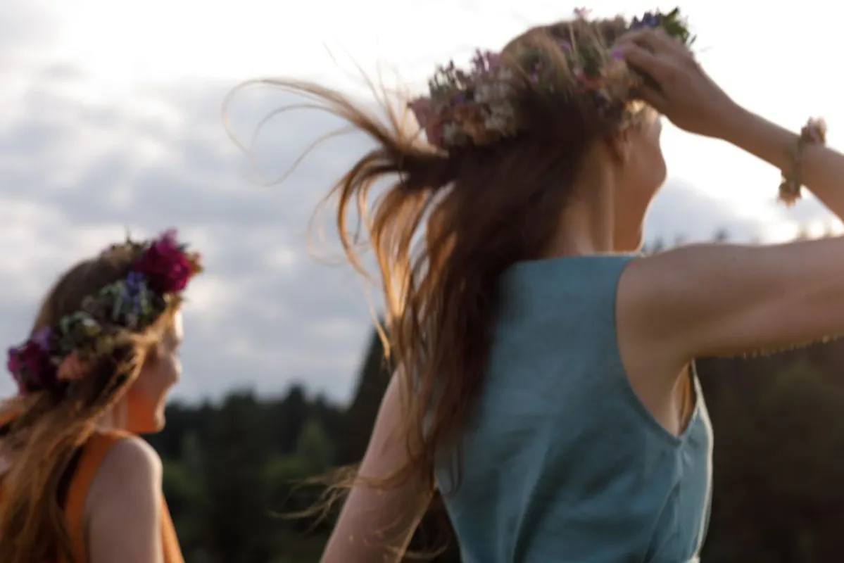 Zwei Frauen mit Blumenhaarkränzen und wehendem Haar