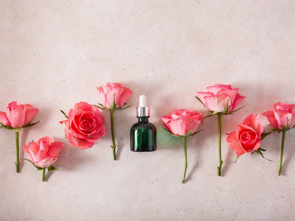 Apricotfarbene Rosenköpfe und in der Mitte ein Aromafläschchen.