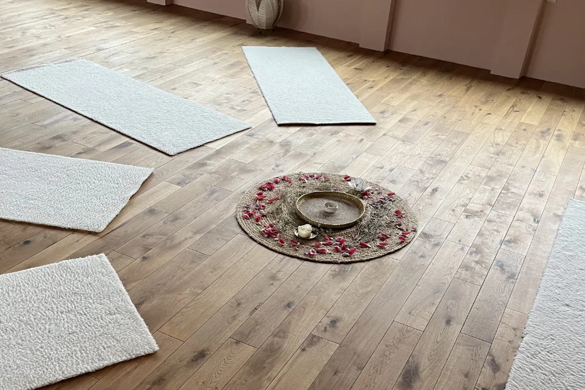 Holzboden des Studios mit ein paar Fellmatten und Teppich in der Mitte mit Blüten