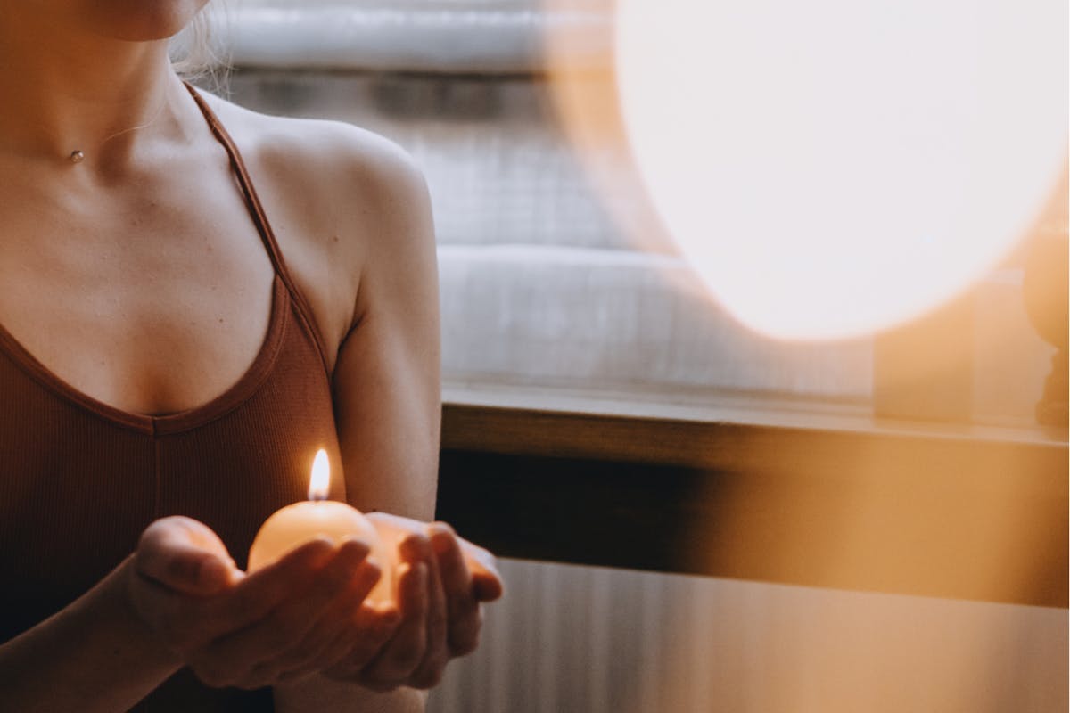 Frau hält leuchtende Kerze in ihren Händen. 