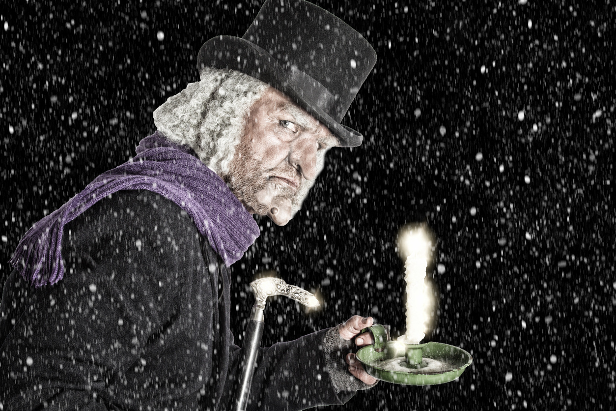 Ebenezer Scrooge hält leuchtende Kerze im Dunkeln.