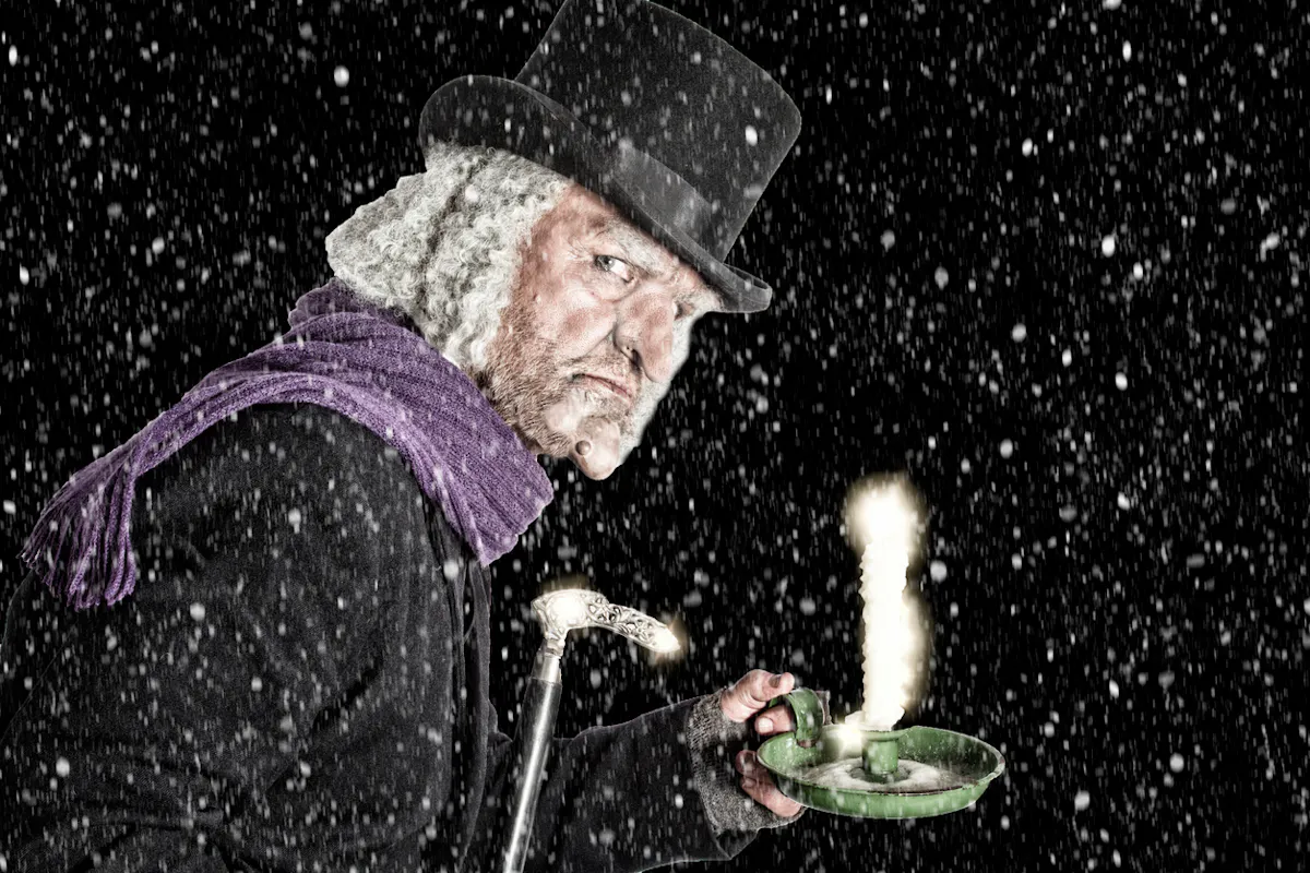 Ebenezer Scrooge hält leuchtende Kerze im Dunkeln.