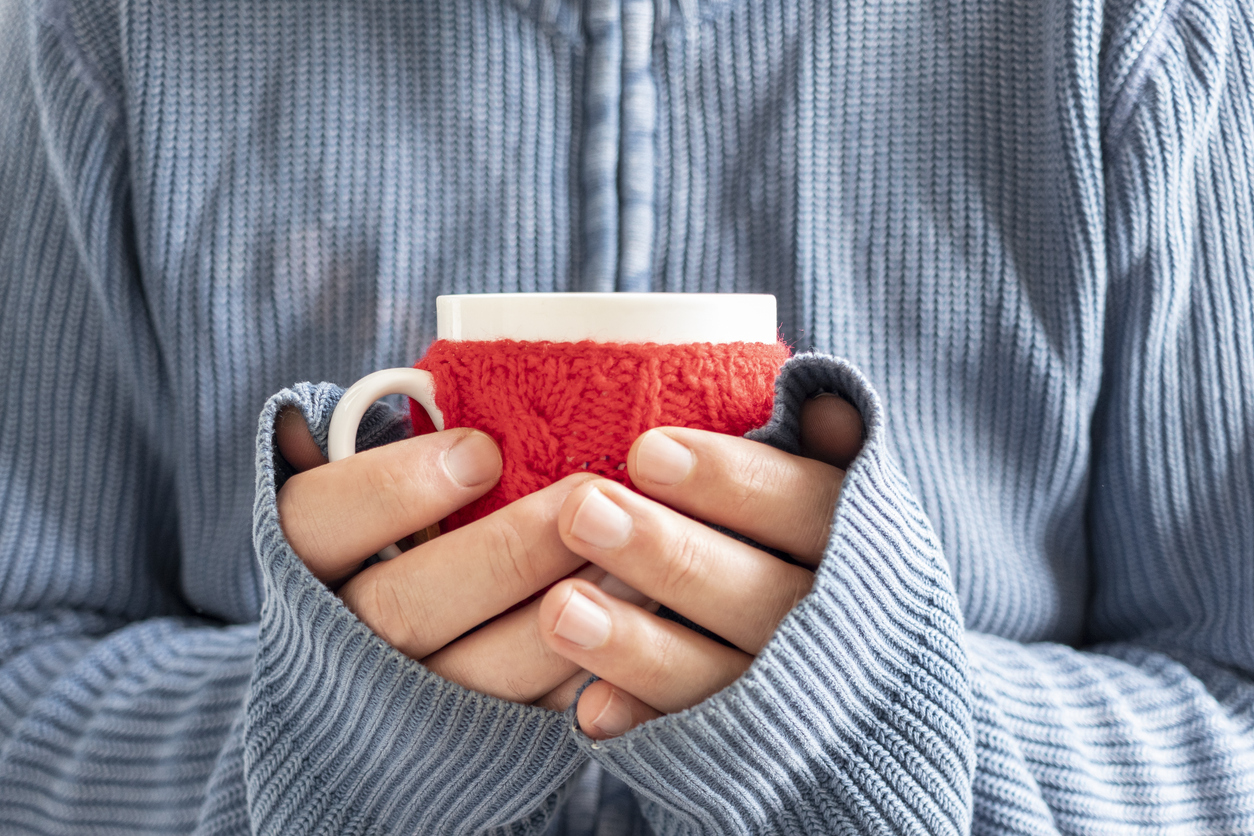 Hände Frau halten Tasse mit Strick eingehüllt. 