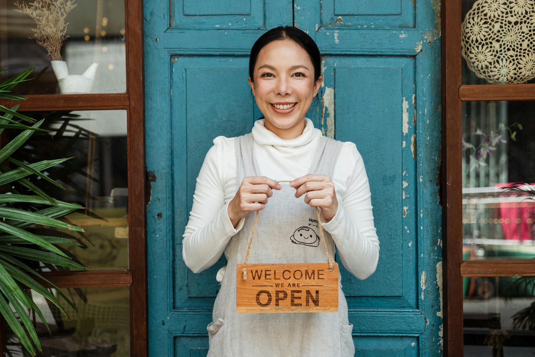 Hospitality restaurant owner holding a sign that says welcome we are open