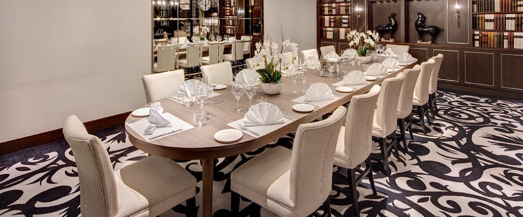 Large dinner table set for dinner with white leather seats. 