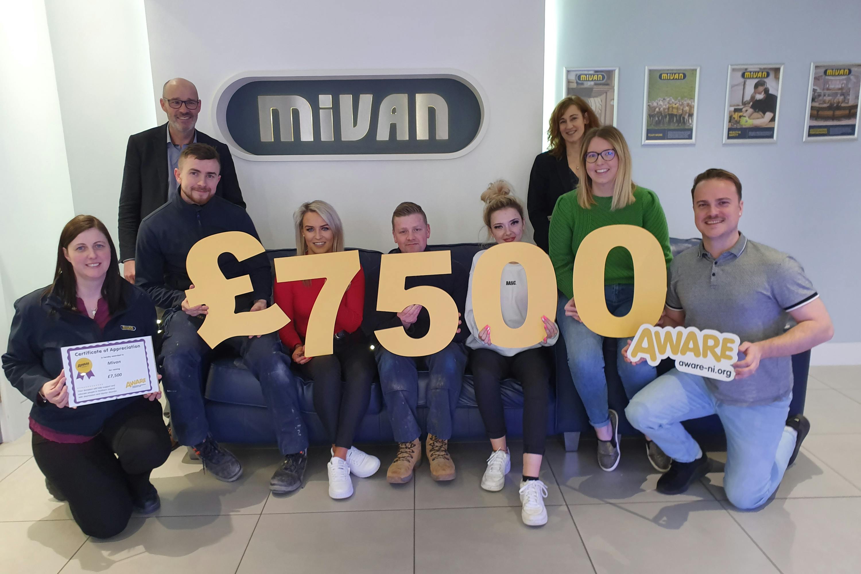 Seven people holding numbers to total £7500 raised for Aware NI, charity partner of the year 2019. 