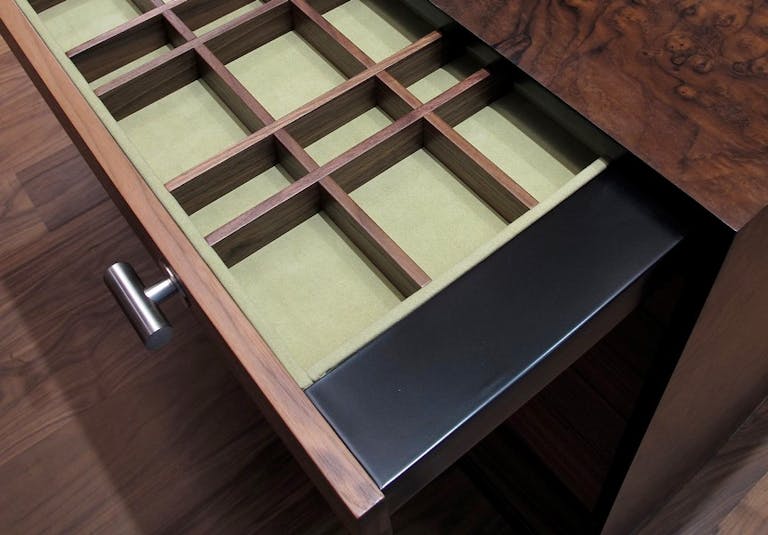 Draw pulled out of table showing bespoke joinery which created compartments to store cutlery . 