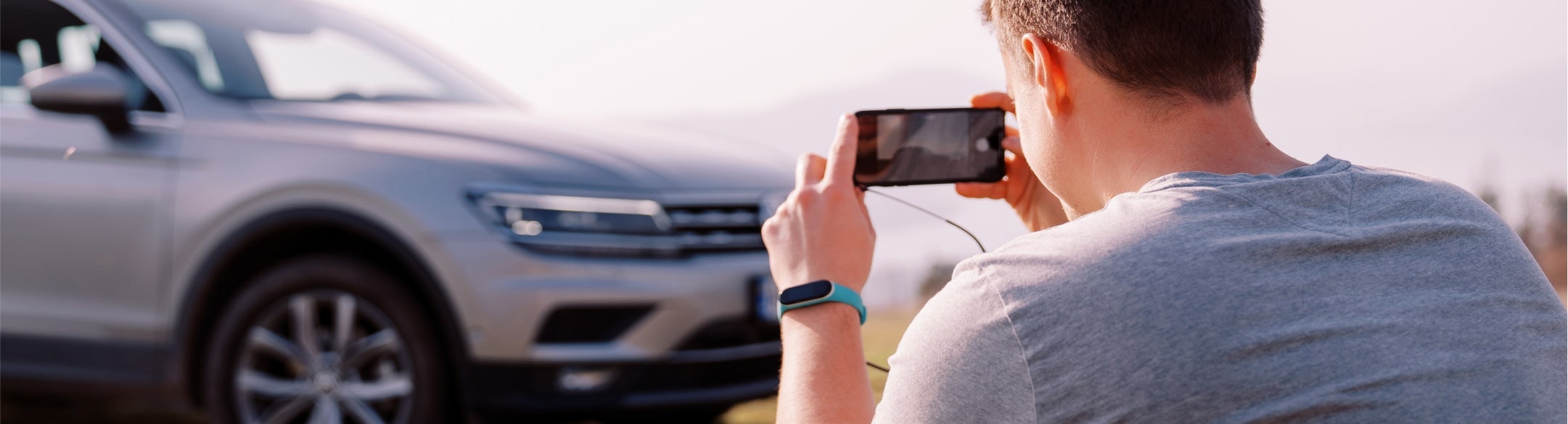 Man taking a photo of a car with his cellphone
