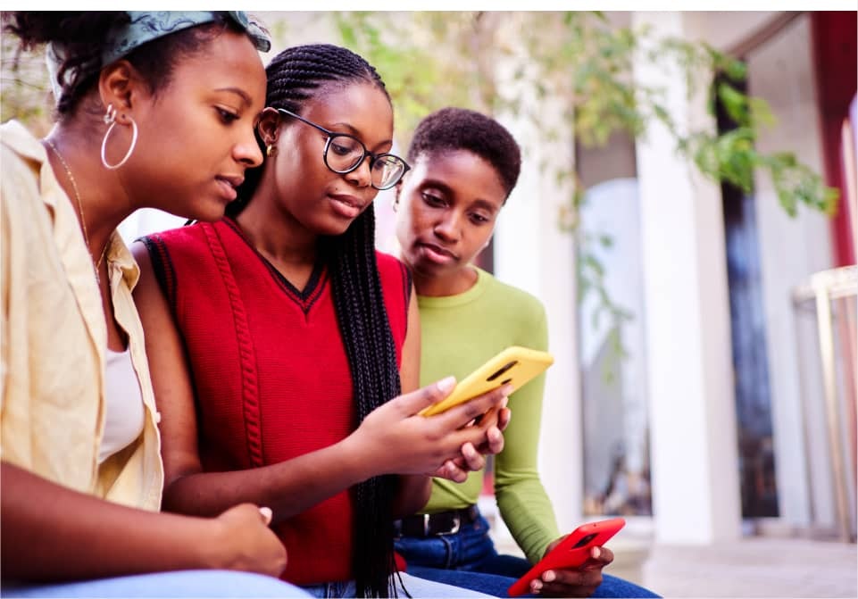 Three woman looking at the middle woman's phone