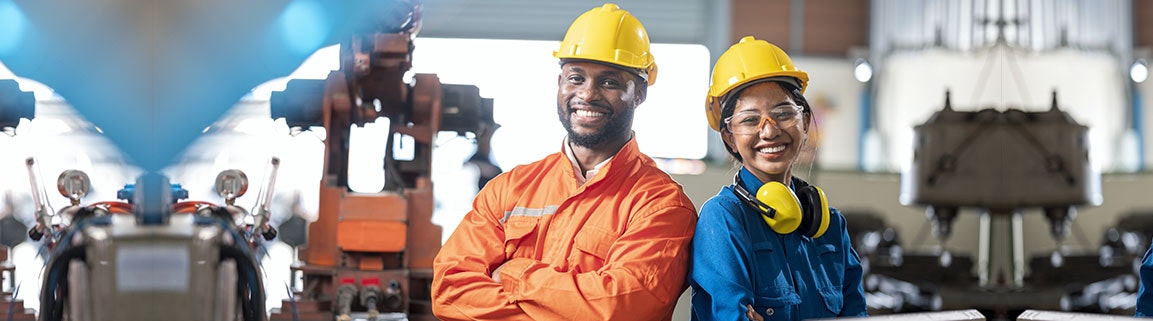 two people working in a factory with equipment in the background