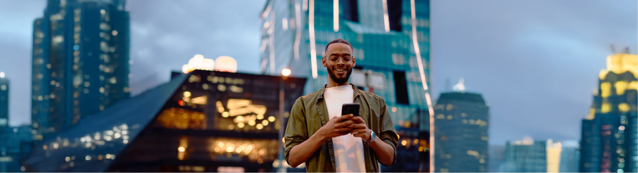 Guy texting on phone standing in front of building