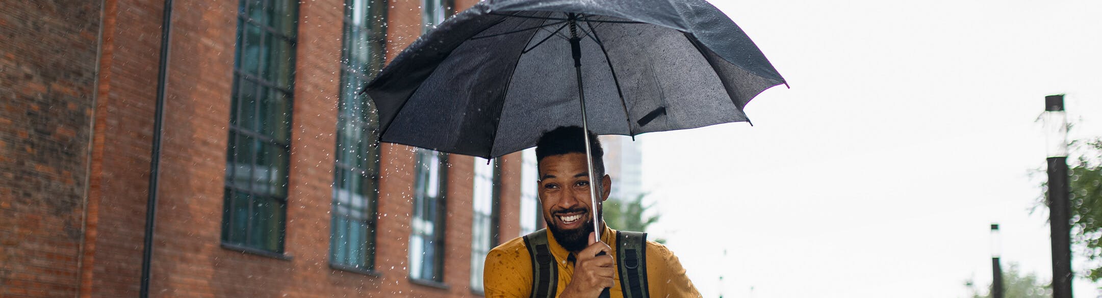 man walking in rain under umbrella