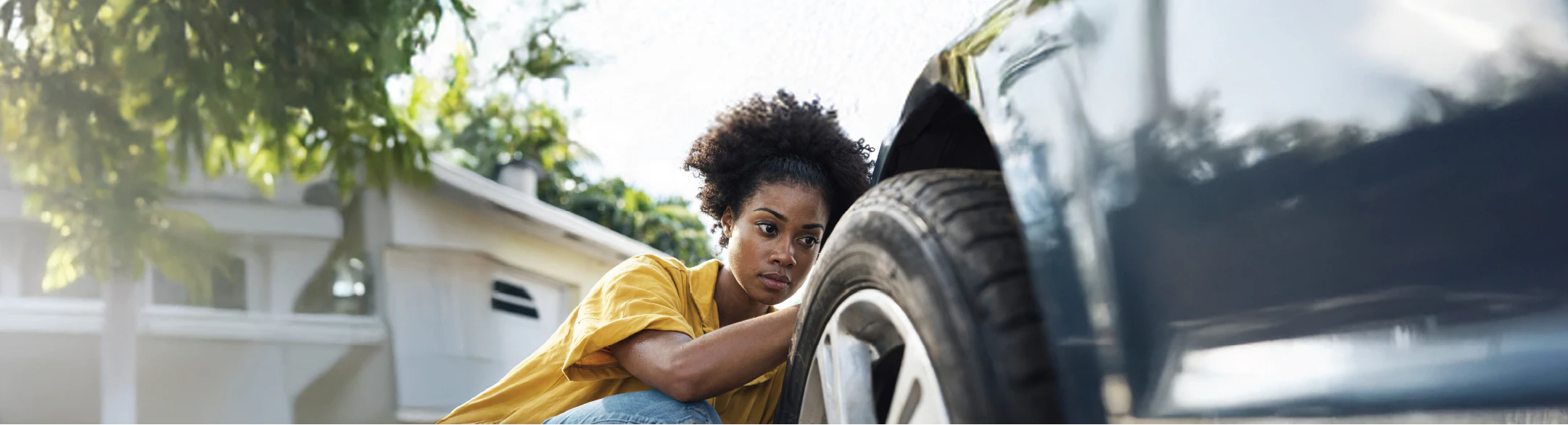 Woman inspecting tyres on car