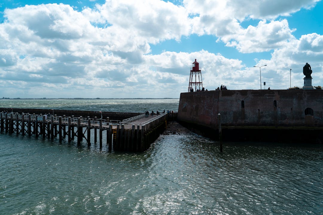 Kust met een pier en aan de rechterkant een gebouw