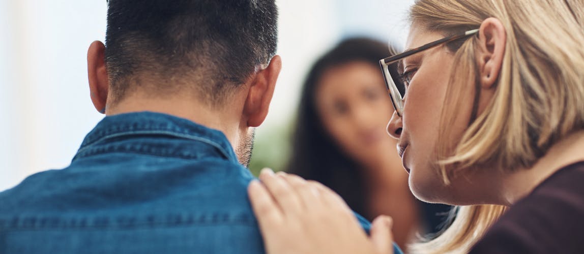 Une femme soutient un homme en mettant sa main sur son épaule