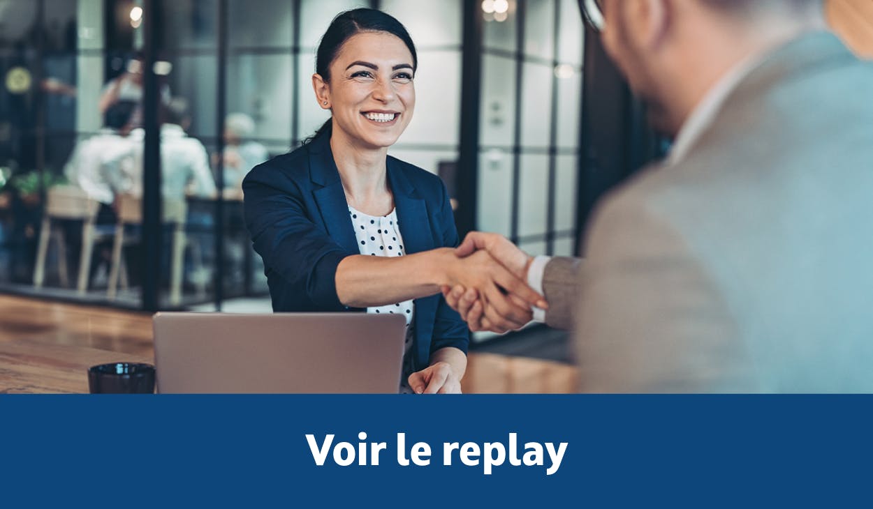 Une femme de face et un homme de dos se serrent la main au-dessus d'une table.