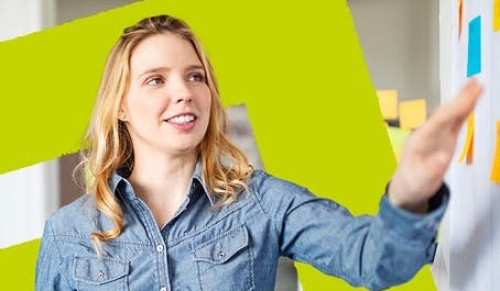 Une femme devant un tableau rempli de post-it