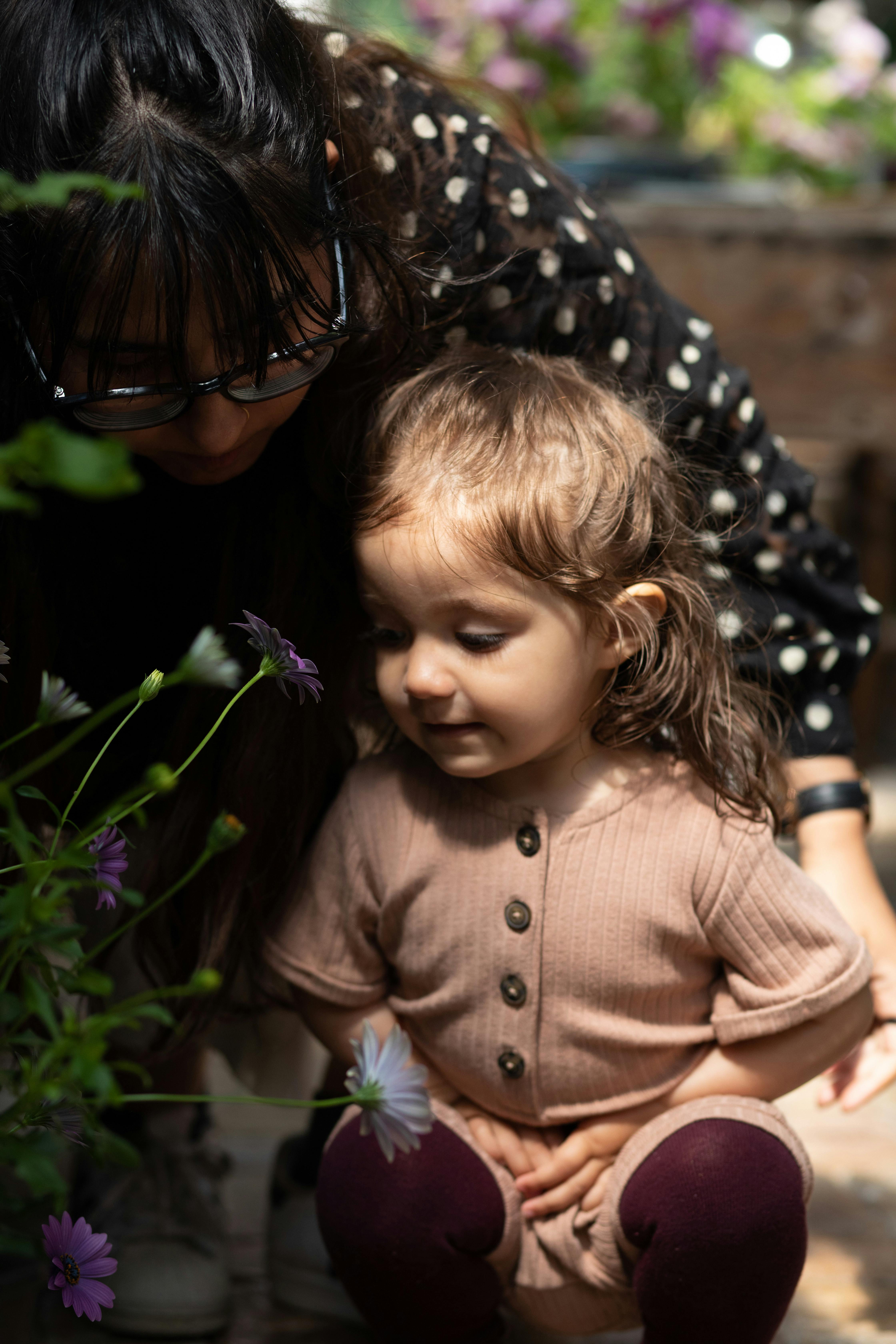 mor og barn sidder på hug og kigger på plante