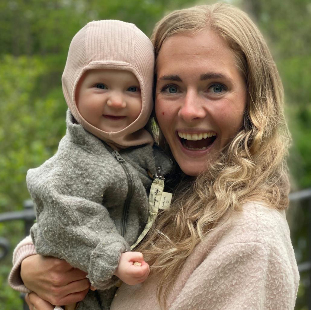 Kvinde holder babypige i favnen og smiler stort