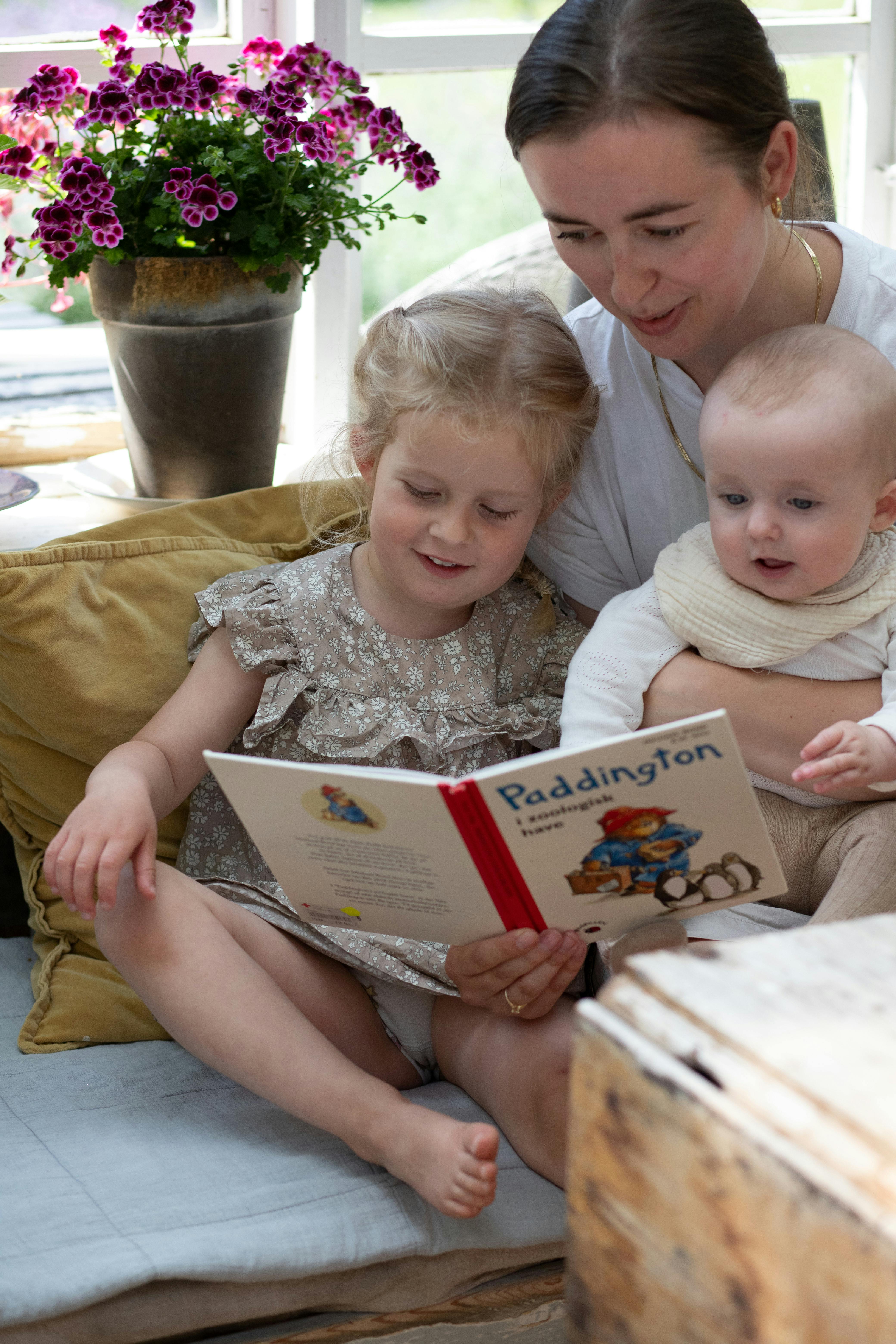 mor læser højt med to børn på skødet