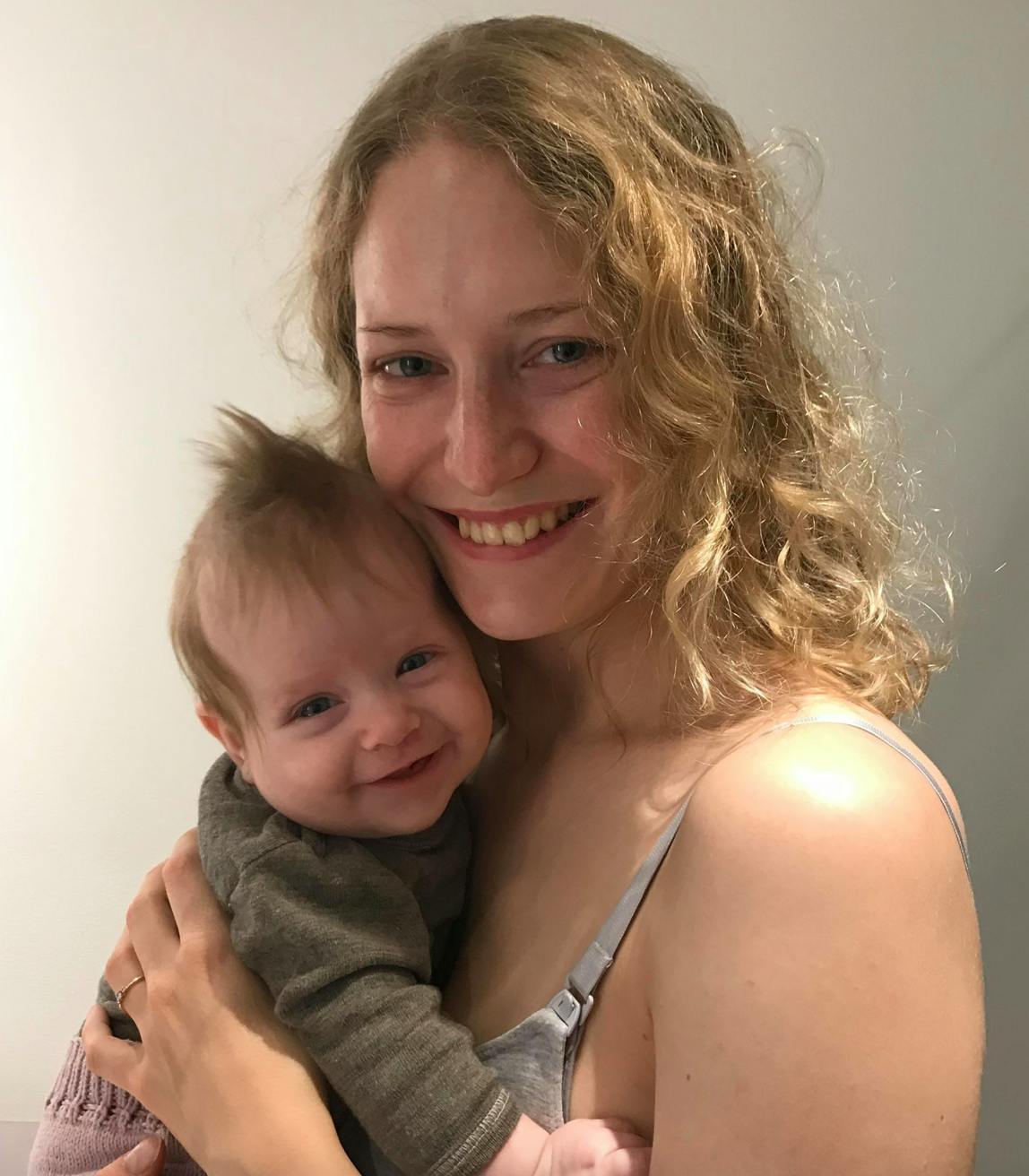 kvinde smiler med sin baby i favnen