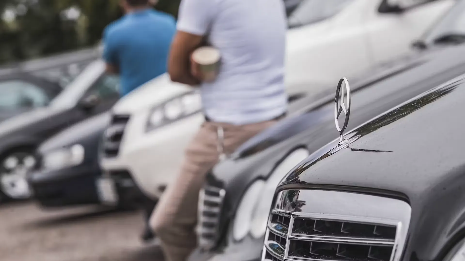 Mann lehnt an Motorhaube eines Autos