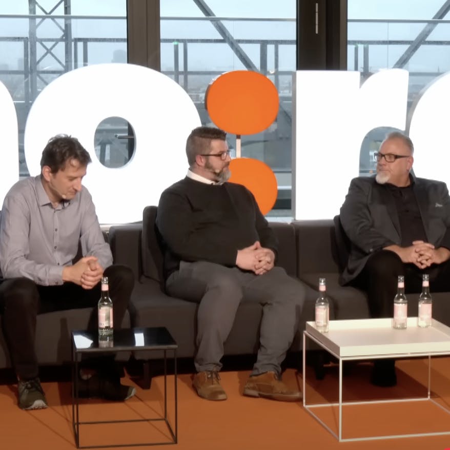 3 Männer sitzen auf eiber Bühnen und diskutieren