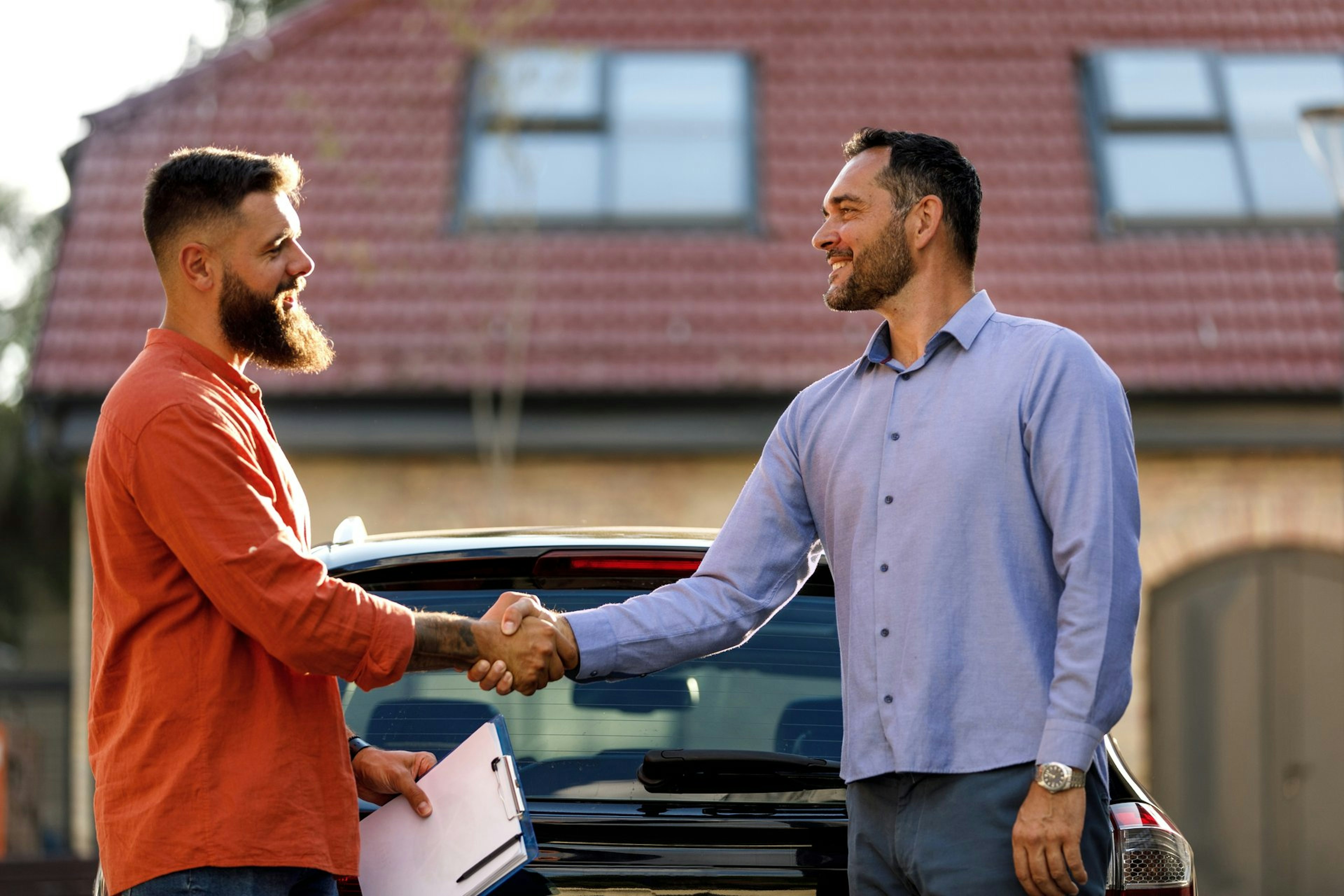 Zwei Männer schütteln Hände vor einem Auto