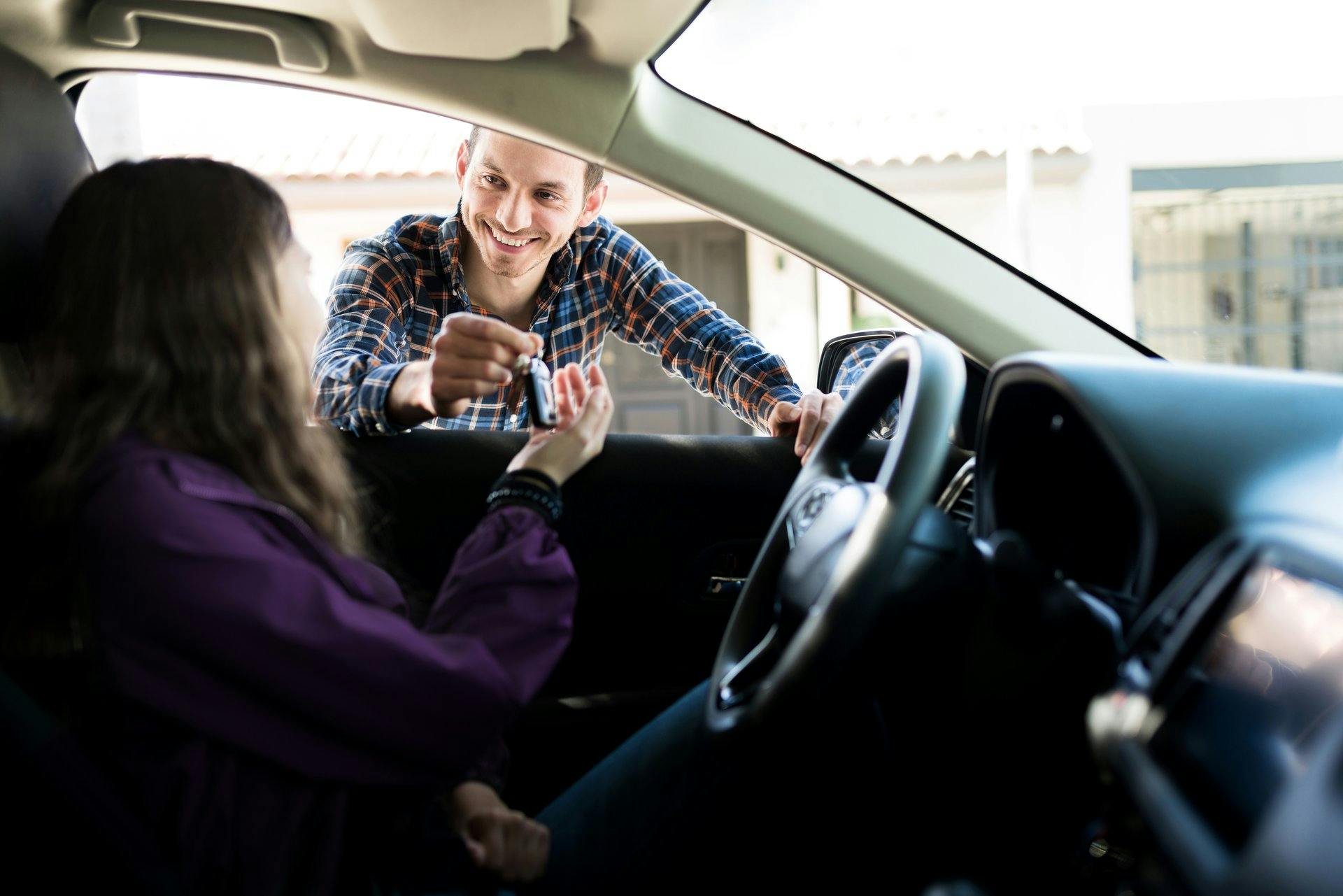 Schlüsselübergabe in ein Auto hinein