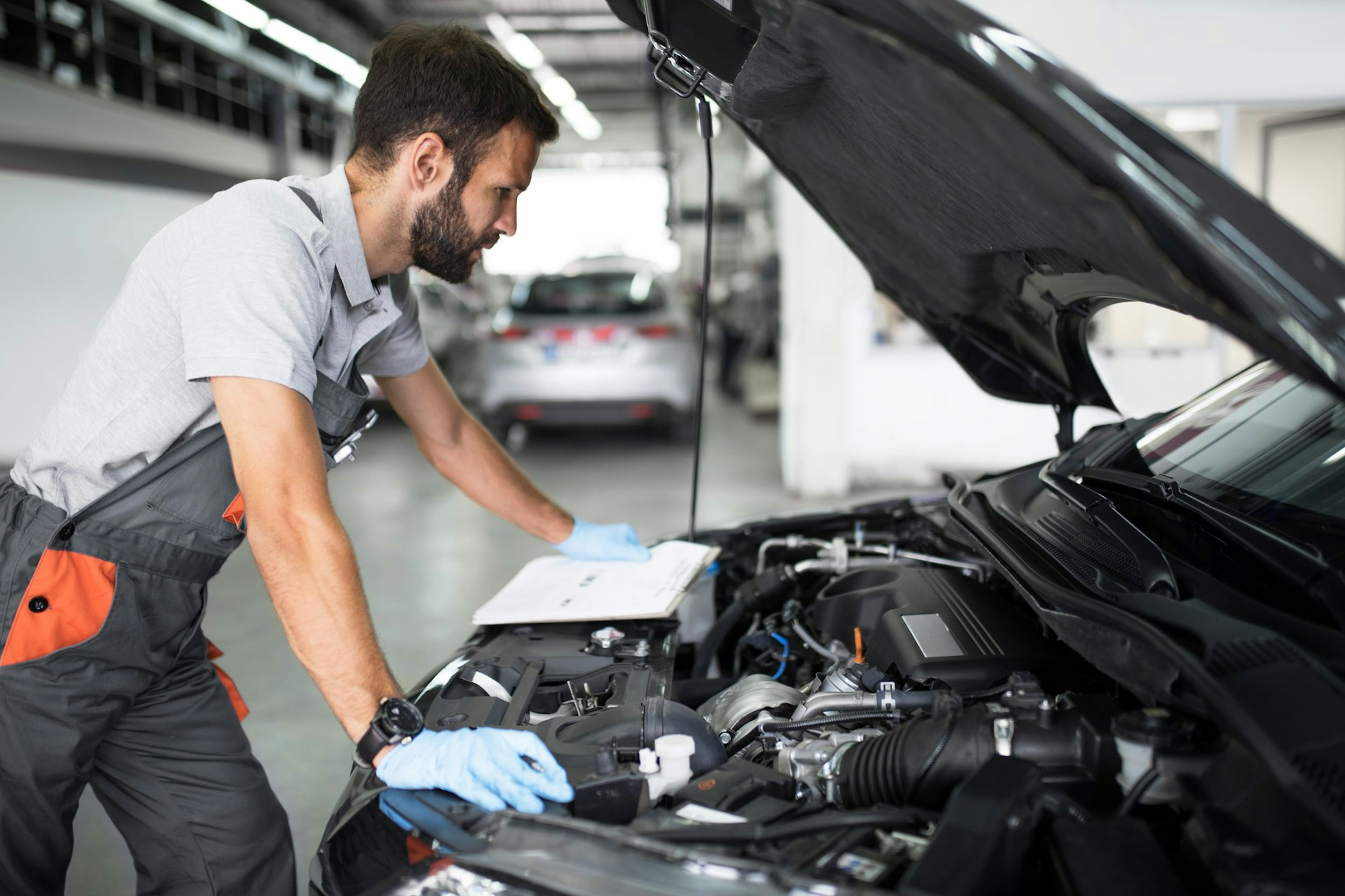 Mechaniker schaut in die Motorhaube eines Autos