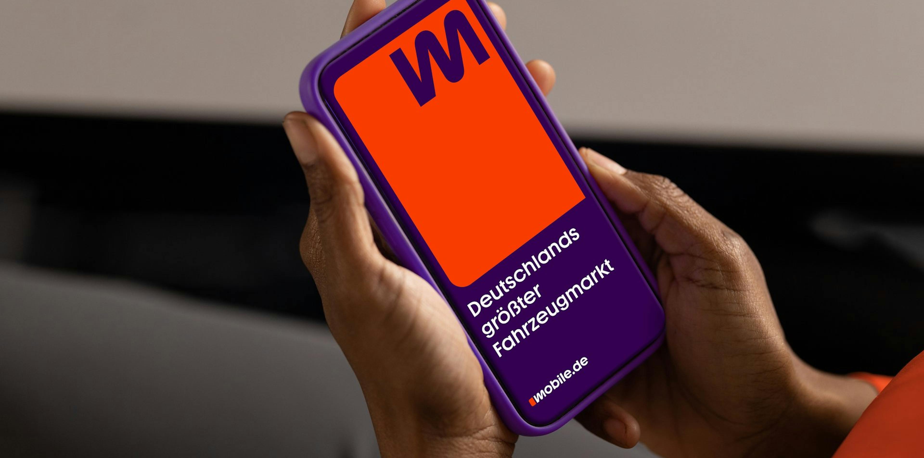 Hände halten Handy mit mobile.de App