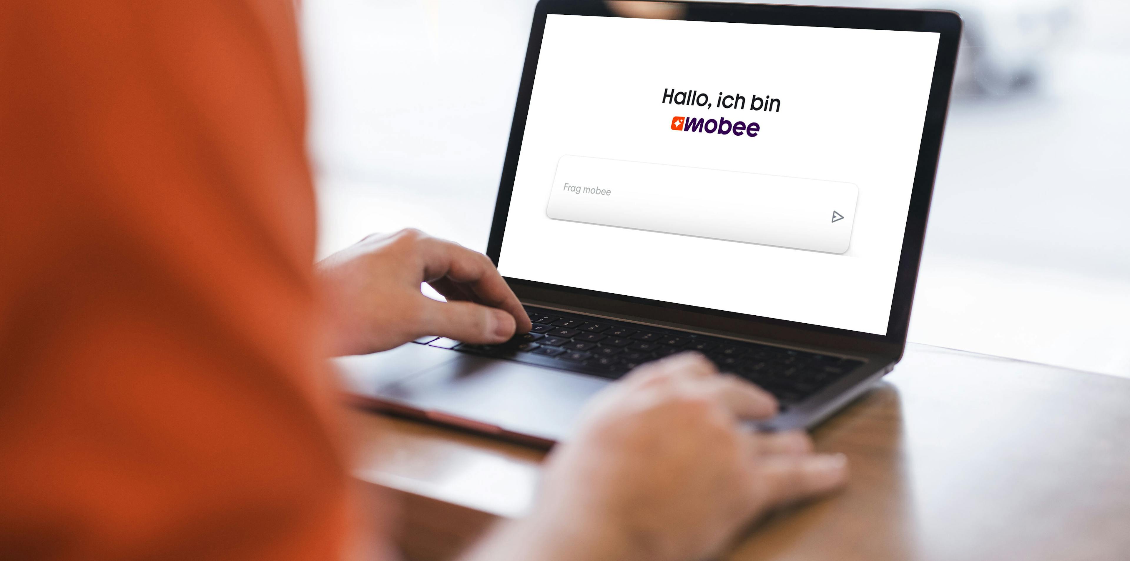 Person sitzt vor einem Laptop und schaut auf den Bildschirm, auf dem ein Eingabefeld zu sehen ist. 