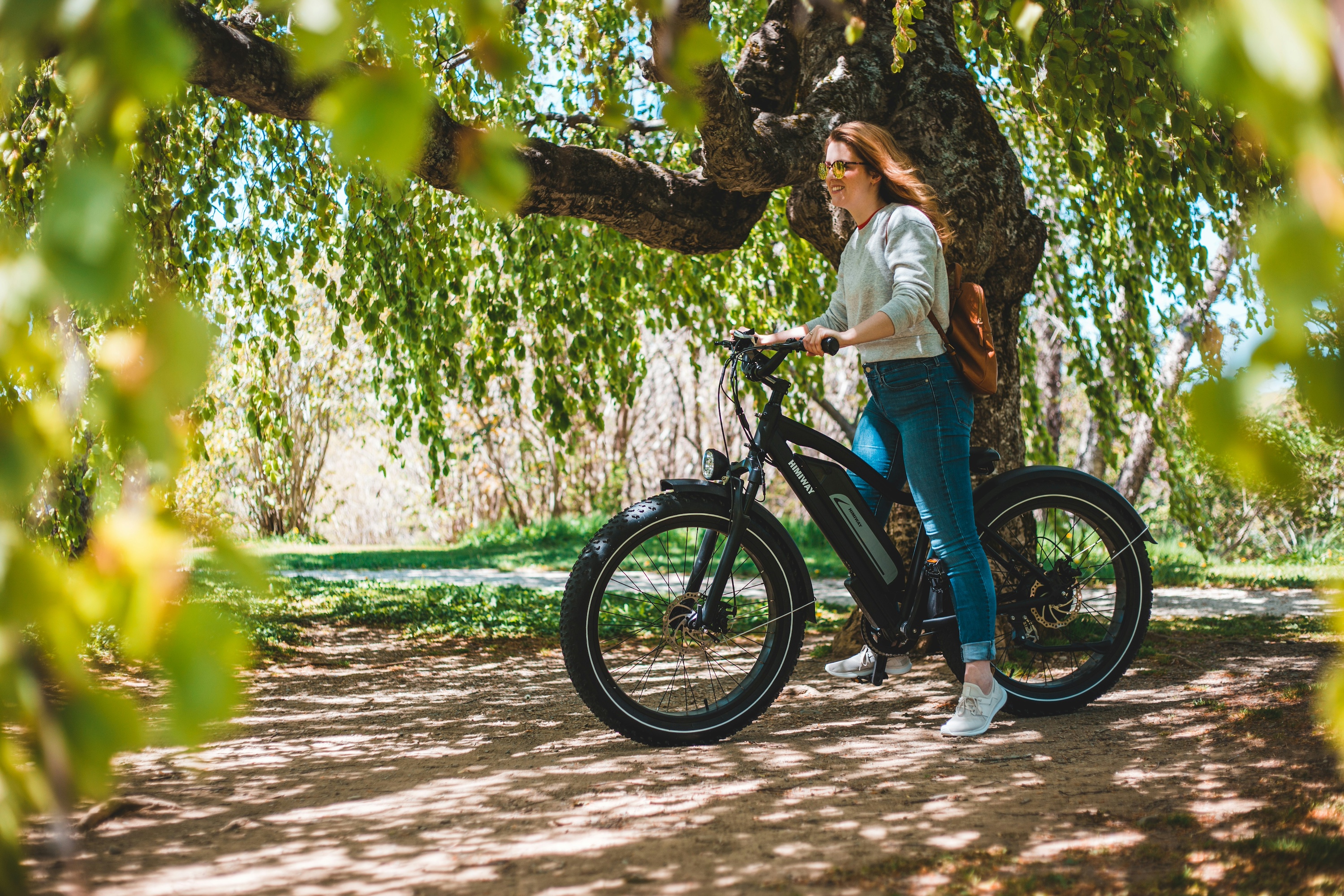 Woman standing under a tree with ebike