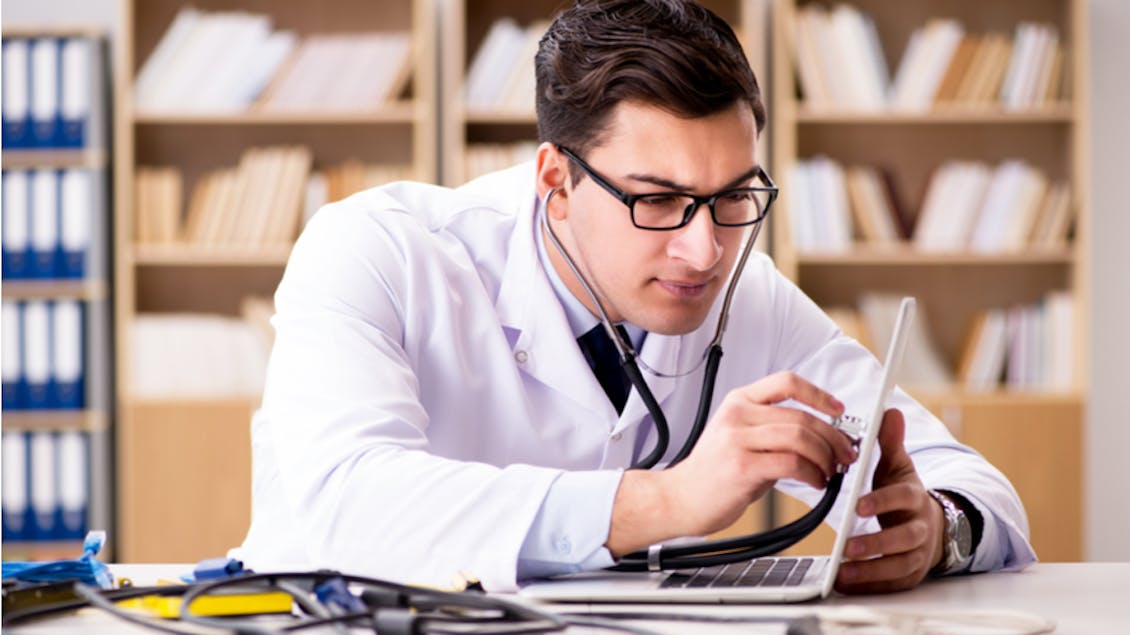 a doctor with stethoscope looking at his computer