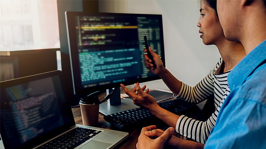 A woman showing a man a code on the computer