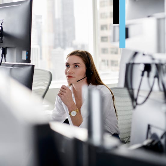 Woman looking at a computer with headphones on