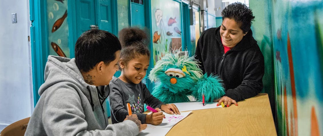 two women drawing with a kid and Rosita from Sesame Street 