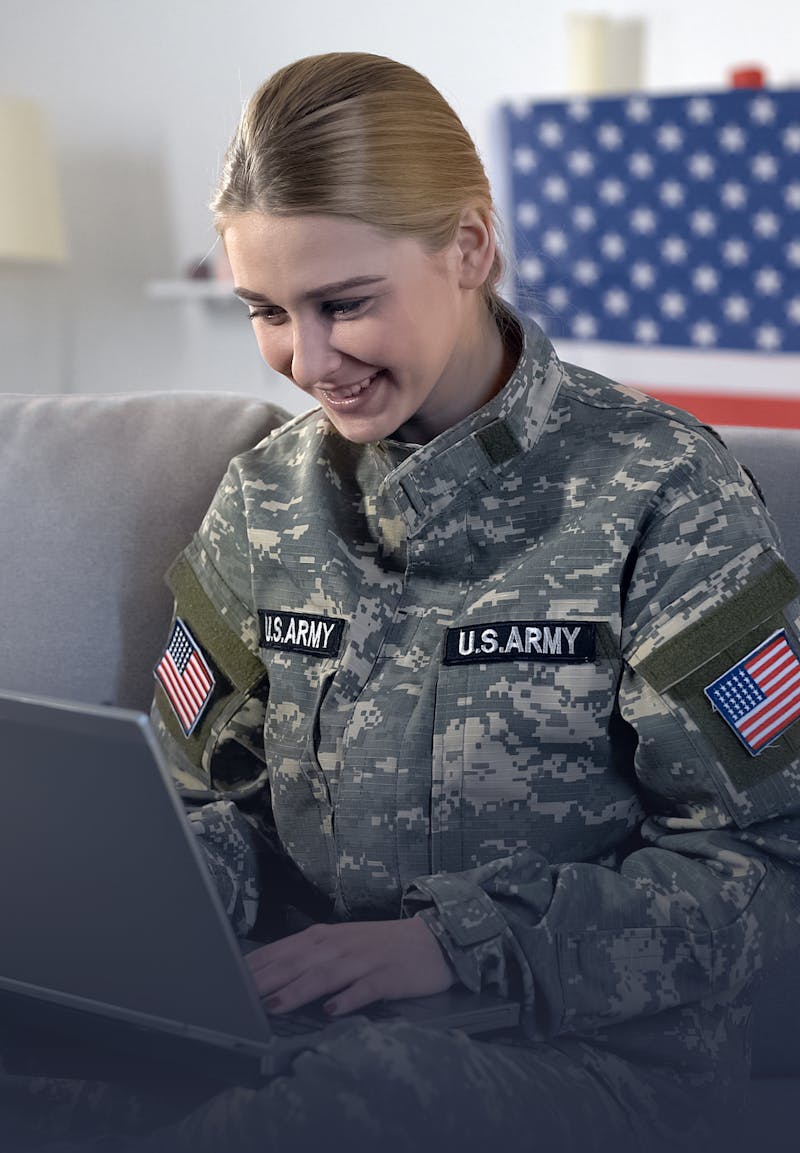 A military woman with a laptop and a US flag on the background