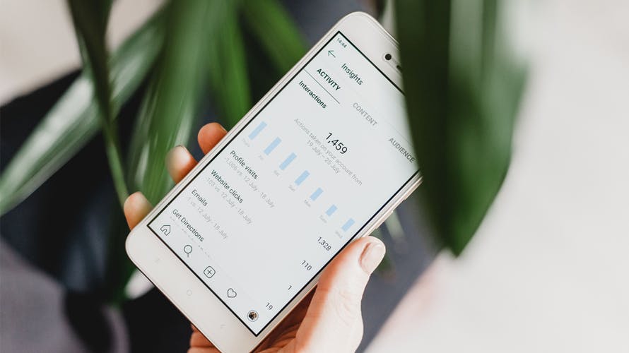 hand holding a cell phone with social media insights