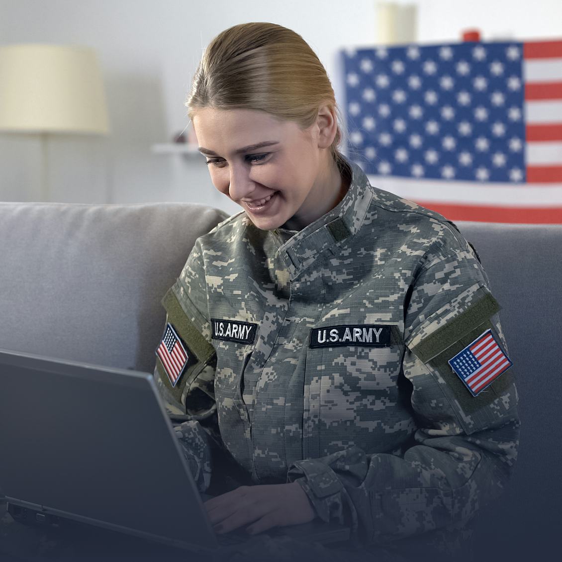 A military woman with a laptop and a US flag on the background