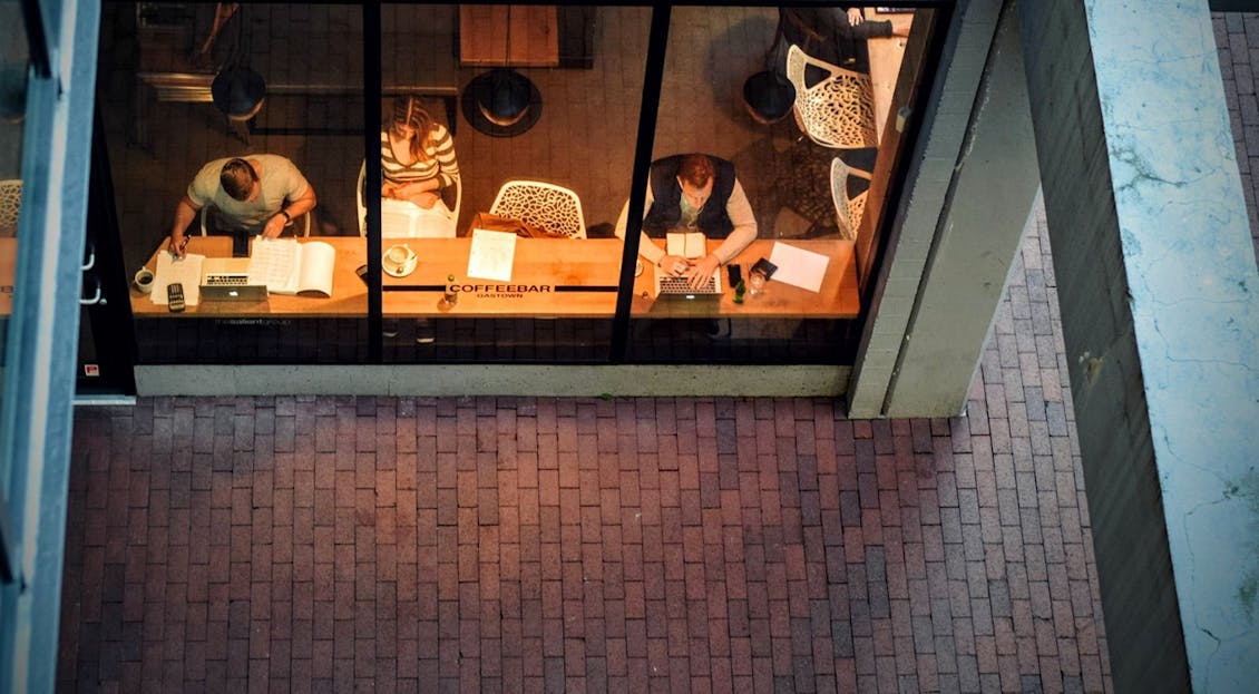 a woman and two men working on a long desk