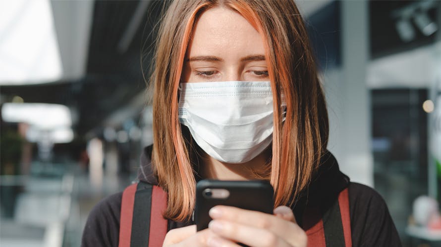 a woman with a mask looking at her phone