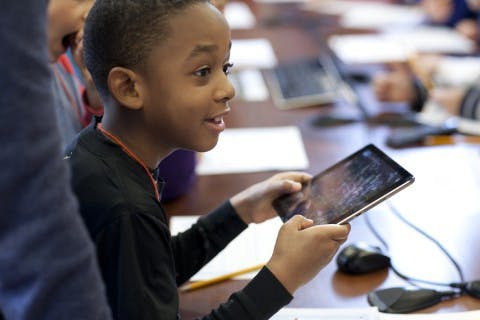 a kid laughing with a tablet on his hand