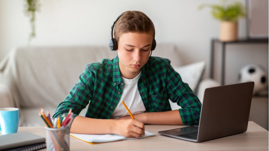 Schoolboy taking notes on an online session