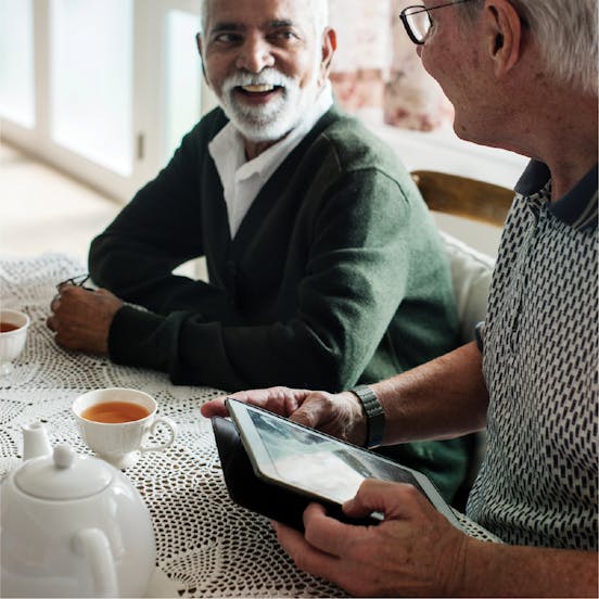 Two elder men looking at each other and smiling