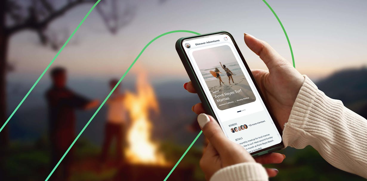 hands holding cellphone in front of a campfire among other individuals