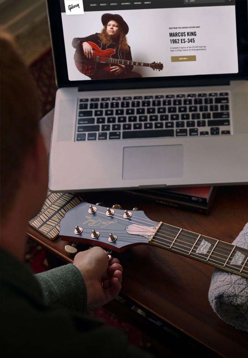 retail experience at Gibson.com on a laptop with a hand holding a guitar