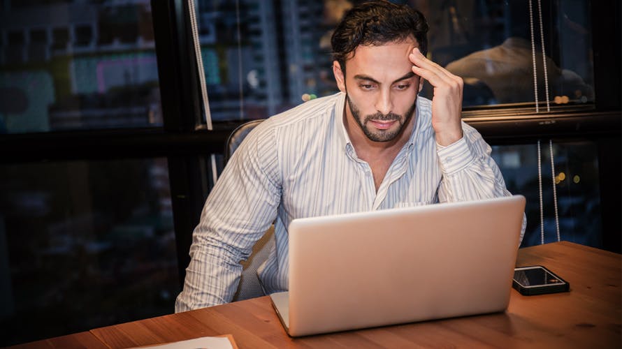 A man looking at his computer in frustration