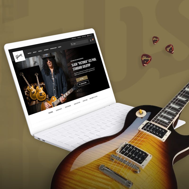 A guitar and a laptop with Gibson.com on the screen
