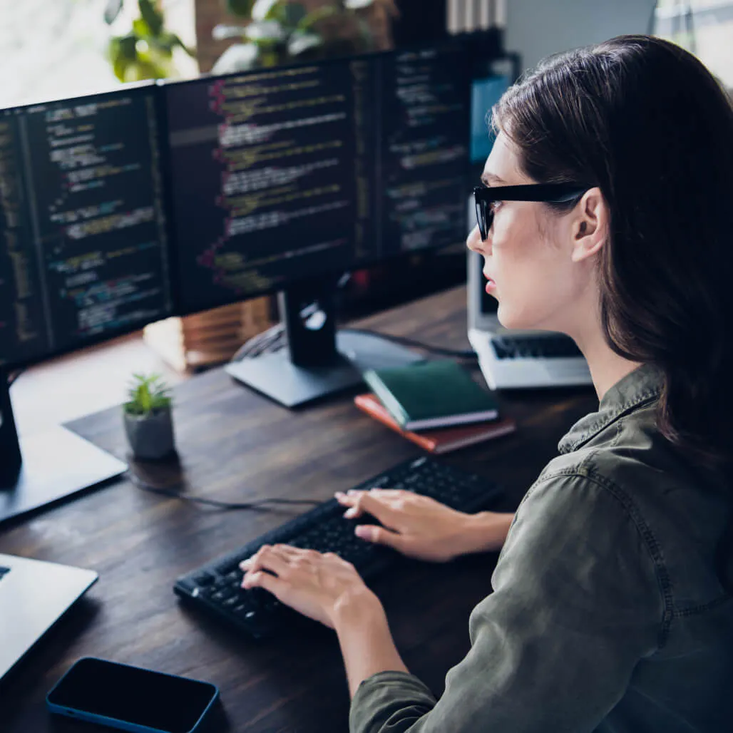 Woman working at a desk with multiple screens